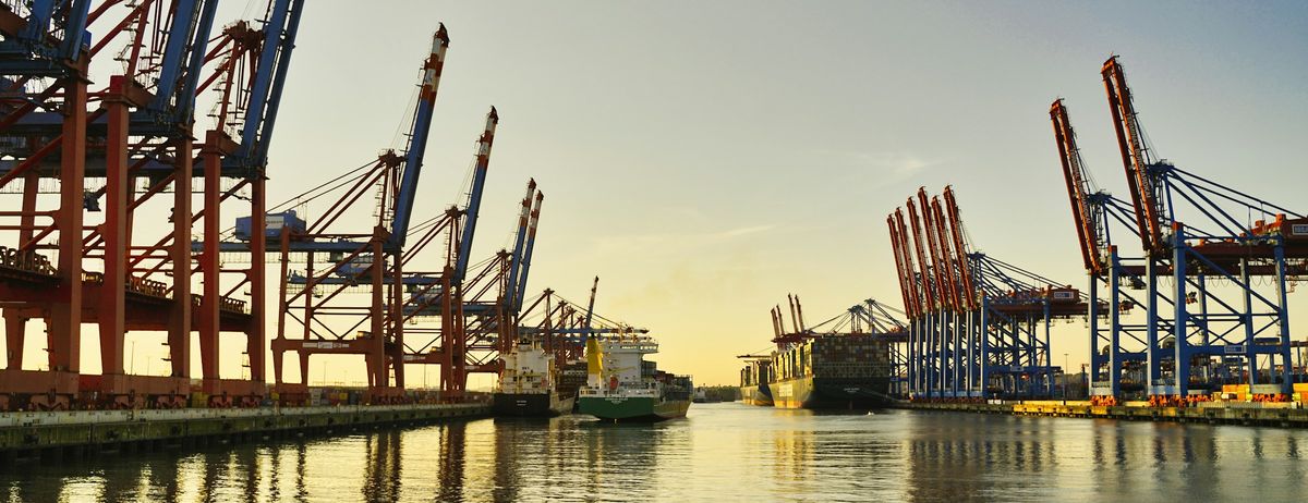 Container port with cargo ship and cranes at sunset